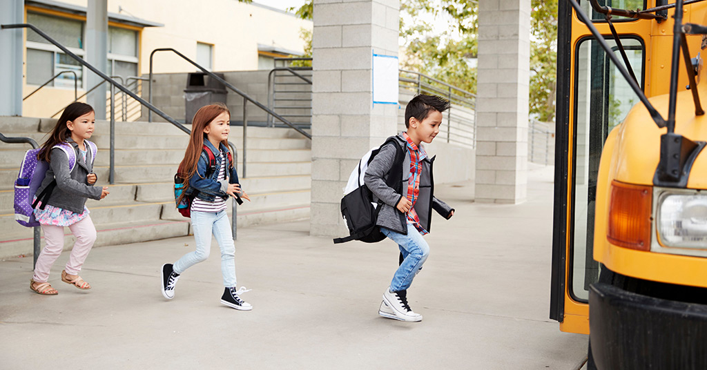 Kids about to get onto the school bus to start their day.
