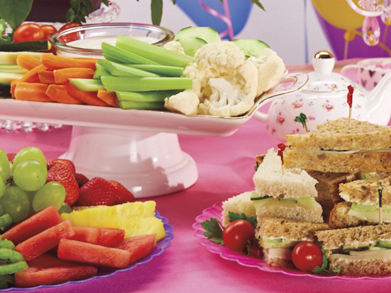 Party trays of vegetables, fruit, and sandwiches.