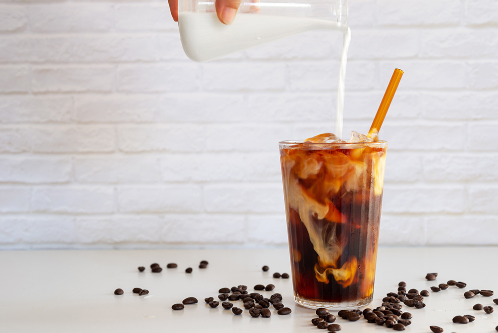 Cold brew coffee with milk being added.