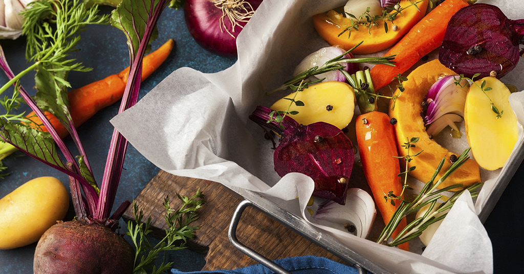 A variety of colorful winter seasonal vegetables in a baking dish seasoned with pepper.