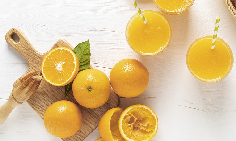 Brightly oranges sliced in half and glasses of orange juice.