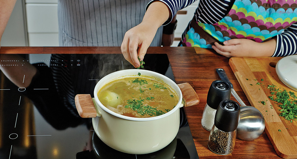 Two people cooking soup together.