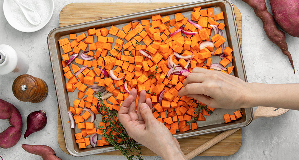 Person preparing sheet pan sweet potatoes.