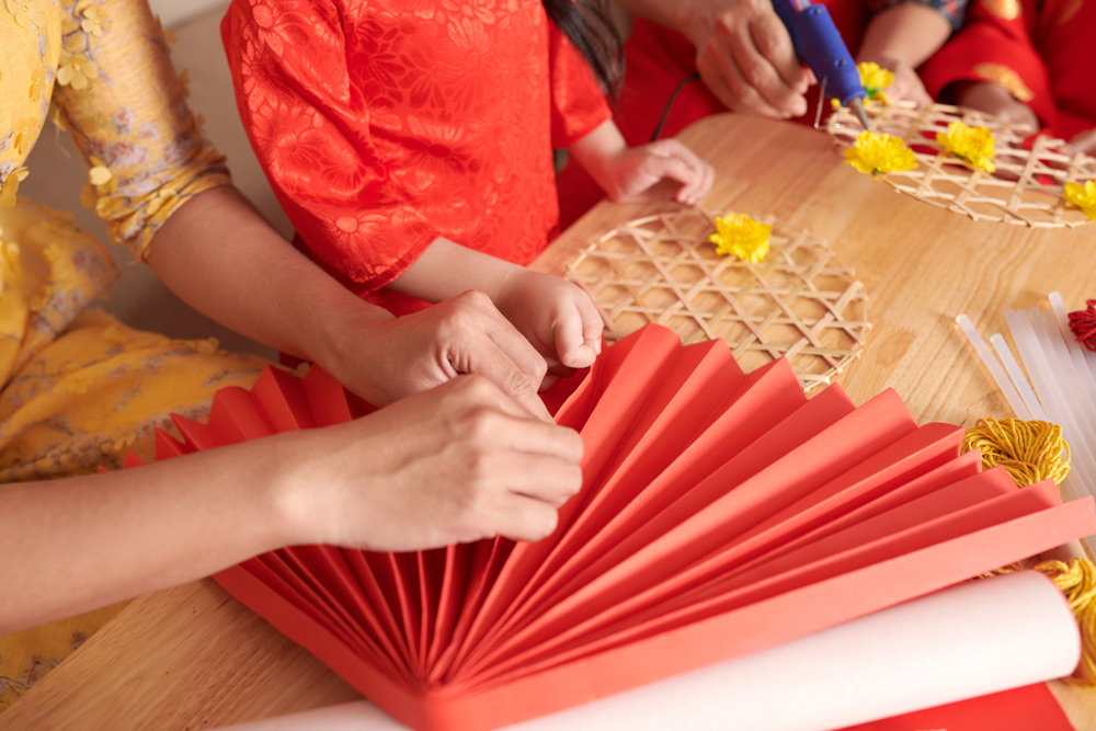 Family making handmade red decorations for lunar new year.