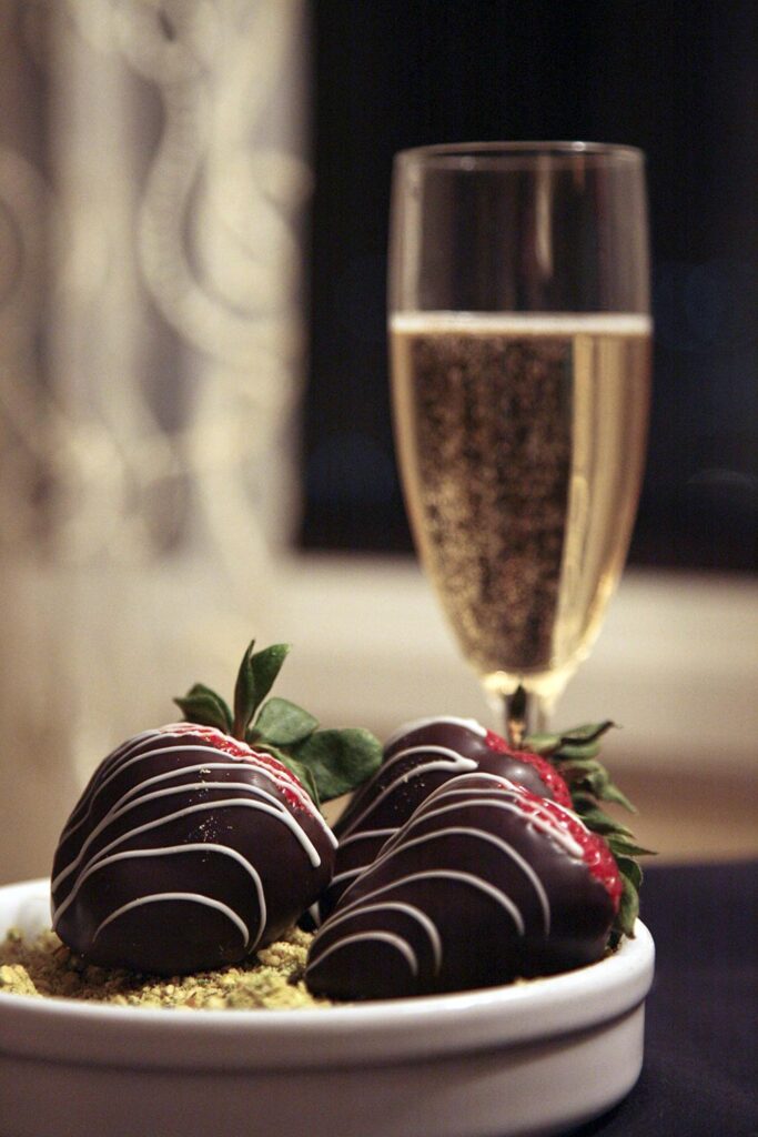 A glass of bubbly Champagne served with dark chocolate covered strawberries.