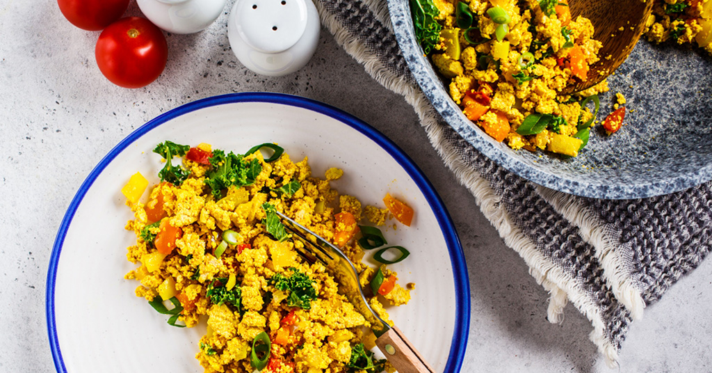 Vegan tofu "egg" scramble made with fresh vegetables served on a plate.