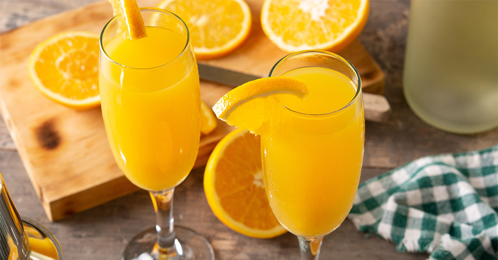 Mimosas made with freshly squeezed or bottled orange juice and brut champagne, served in a champagne flute for friends.