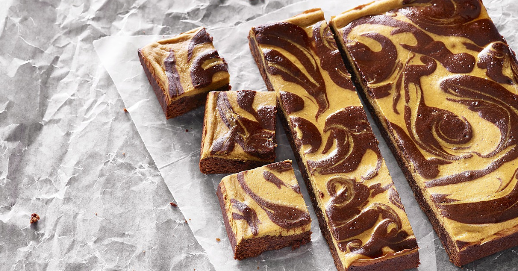 Pumpkin cheesecake swirl brownies on top of parchment paper. 